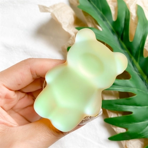 Détail d'un support de téléphone ours vert clair avec texture mate aurore tenu à la main