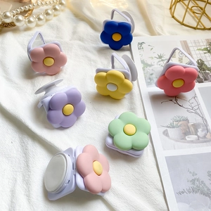 Detail showing colorful matte flower phone socket grips on a soft white fabric background