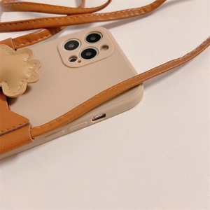 Gros plan sur la coque iPhone bandoulière beige avec porte-carte marron et détail fleuri