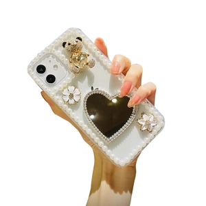 Luxury iPhone case with pearls, 3D golden bear, heart mirror, and white flower accents