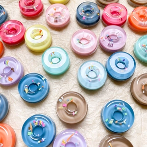 Flat lay of colorful donut-shaped phone grips with rainbow glitter on textured paper