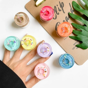 Minimalist donut-shaped phone grip stand in seven vibrant pastel colors on a white desk