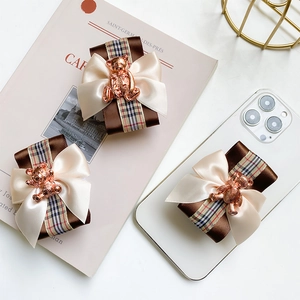 Detailed view of satin hair bows with metal bear charm and classic plaid ribbon accents