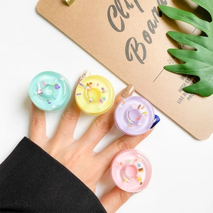 Detail of doughnut phone grip holders in pastel mint green and lavender colors on fingers