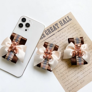 Detail of elegant bow phone stand featuring a metallic rose gold bear and plaid ribbon