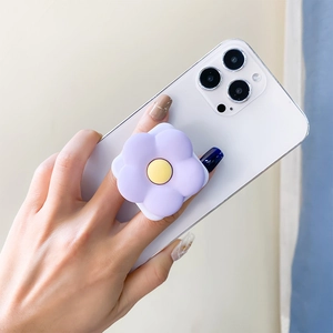 Detailed view of hand holding a purple flower phone grip with yellow center mirror