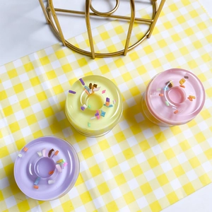 Close-up of three colorful donut-shaped scented candles in clear glass containers