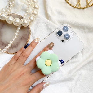Detail of light green floral phone grip stand on a white smartphone with soft lighting