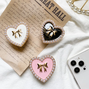 Close-up of heart-shaped phone grips with pearl edges and golden 3D bow details