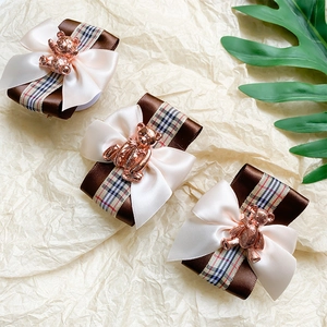 Detail of three bow hair accessories with metal bear charms on textured background