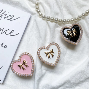 Detailed view of heart-shaped phone grips with pearl border and golden metal bow accents