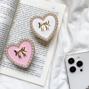 Detail of heart-shaped phone stands with pearl borders and golden bow accents on a book