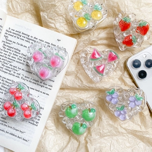 Detail of transparent heart-shaped phone grips with 3D resin fruits on textured background