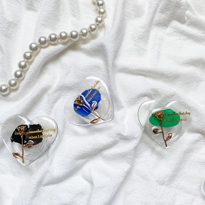 Close-up of heart-shaped phone grips with gold roses on black, blue, and green bases