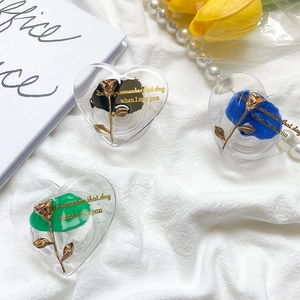 Detailed view of heart-shaped phone grips with metallic roses on white fabric