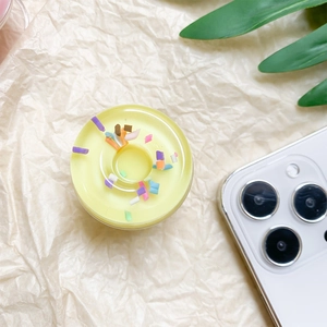 Close-up of cute doughnut-shaped phone socket grip with colorful sprinkles on cream paper
