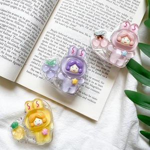Detail of three cartoon resin fruit rabbit astronaut phone grip accessories on book