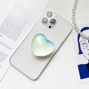 Macro shot of heart-shaped laser holographic phone grip with gradient colors on a white phone