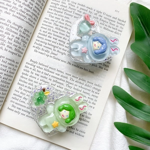 Close-up of heart-shaped glitter phone grips with cute cartoon girl designs on an open book