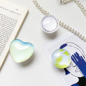 Laser starry glass phone grip set with heart and round designs on marble surface