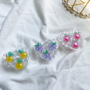 Detailed view of heart-shaped resin phone grips with 3D fruit designs on white fabric