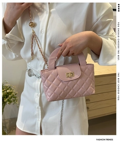 Detail of pink quilted shoulder bag with gold twist lock and chain strap on a model