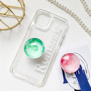 Clear phone case with Romantic text and two marble pattern grip stands on leather background
