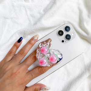Close-up of heart-shaped resin phone grip with 3D pink peaches and clear ice cubes
