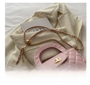 Detail of pink quilted handbag with gold turn-lock and adjustable chain strap on beige blazer