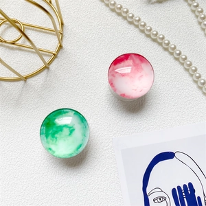 Detail view of crystal glass phone sockets in pink and green with artistic ink texture