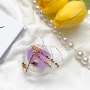 Detailed view of a heart-shaped phone grip featuring a gold rose and purple accents