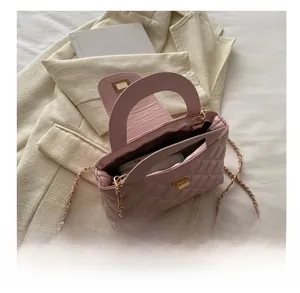 Detailed view of pink quilted handbag interior capacity with gold chain and ball charm