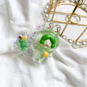 Detail of heart-shaped resin phone grip with green cartoon rabbit and purple sequins