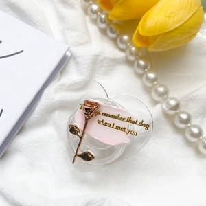 Close-up of heart-shaped phone grip featuring a rose gold flower and romantic message