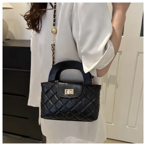 Black quilted crossbody bag featuring a golden chain strap with decorative metal ball