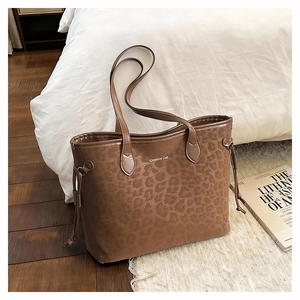 Detail of Creative Cat metal logo and animal pattern texture on a brown tote bag