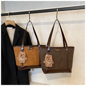 Detail of suede tote bags in caramel and dark green with cute bear charms attached