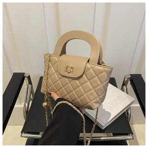 Beige quilted shoulder bag with chain strap and rounded top handle in modern setting