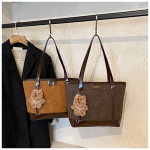 Detail of suede tote bags with glossy leather trim and cute plush bear charms