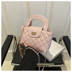Pink quilted shoulder bag with gold chain strap and metal lock shown in lifestyle setting