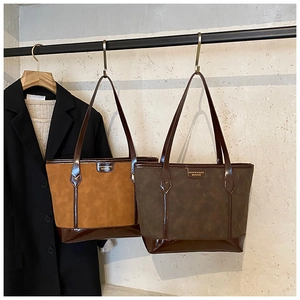 Detail of caramel and dark coffee tote bags hanging against a minimalist suit backdrop