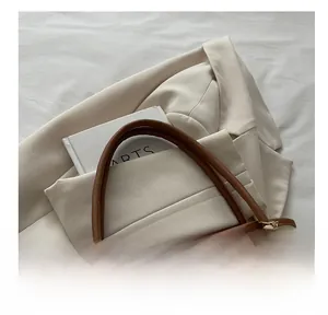 Detail of off-white tote bag with brown leather handle and cute plush charm decor