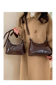 Dettaglio della borsa a tracolla marrone lucida con catena in metallo e scritta FASHION & BAGS
