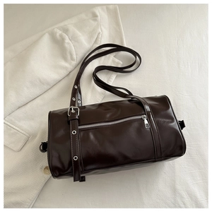 Close-up of a dark brown cylindrical shoulder bag with silver buckles and glossy finish