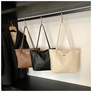 Gros plan de sacs cabas en similicuir grainé en marron, noir et beige avec logo métal
