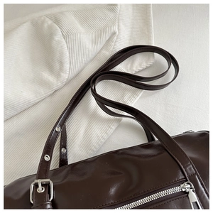 Detail of dark brown leather Boston bag showing silver zipper and adjustable shoulder strap