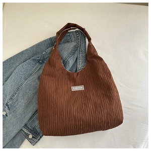 Detail of caramel pleated tote bag with fashion label and textured fabric finish