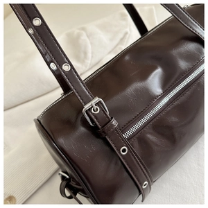 Close-up of glossy brown Boston bag with silver hardware and metallic eyelets details