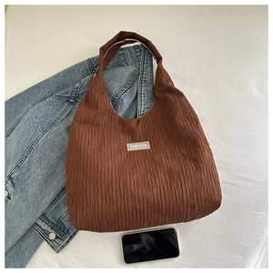 Détail d'un grand sac cabas plissé marron avec une étiquette blanche FASHION
