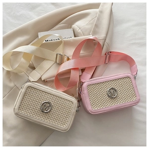 Detail of woven crossbody bags featuring a metallic M logo and wide fabric shoulder straps